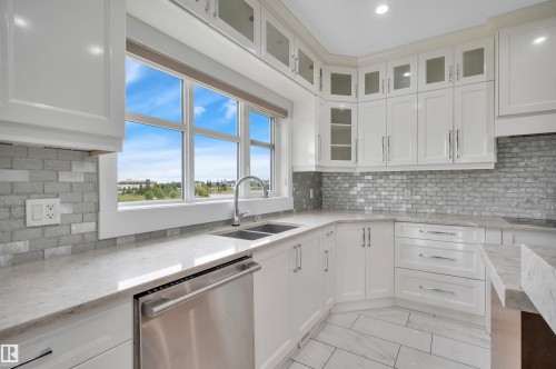 White cabinetry with glass-front uppers, stainless steel appliances, stone countertops, and a subway tile backsplash - 9054 24 Avenue Sw, Edmonton, AB 