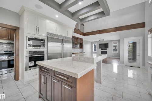 Kitchen featuring a two-tone island with light countertops, stainless steel appliances, and white upper cabinetry - 9054 24 Avenue Sw, Edmonton, AB 