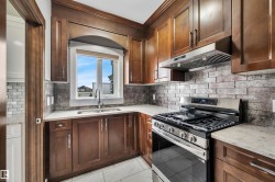 Rich wood-finish cabinetry, stainless steel gas range, and a rectangular undermount sink - 