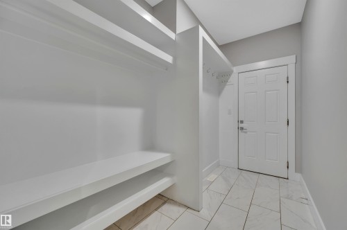 Built-in shelving, integrated coat hooks, white panel door, and tile flooring - 9054 24 Avenue Sw, Edmonton, AB 