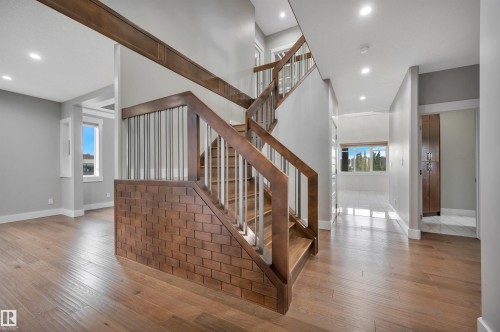 Wood-finish flooring throughout, a wood staircase with metal balusters, recessed ceiling lighting, and a built-in wood cabinet - 9054 24 Avenue Sw, Edmonton, AB 