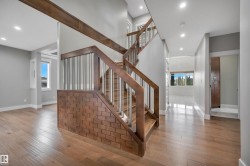 Wood-finish flooring throughout, a wood staircase with metal balusters, recessed ceiling lighting, and a built-in wood cabinet - 