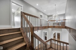 Wood-finish staircase with dark wood railings and metal balusters - 