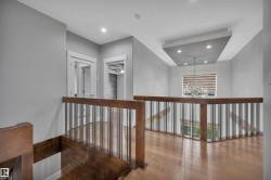 Hardwood flooring, wood and metal railing, recessed lighting, tray ceiling with recessed lighting, and a contemporary chandelier - 