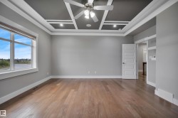 Coffered ceiling with recessed lighting and a ceiling fan, large window with water scenery, wood-finish flooring, and a paneled interior door - 