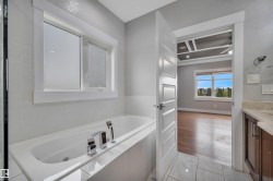 Soaking tub with chrome fixtures, tiled surround, and large window - 