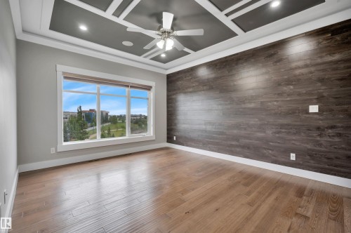 Wood-finish flooring, coffered ceiling with recessed lighting, ceiling fan, expansive window, and accent wall with horizontal wood paneling - 9054 24 Avenue Sw, Edmonton, AB 