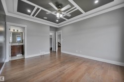 Wood-finish flooring with a decorative tray ceiling and recessed lighting - 
