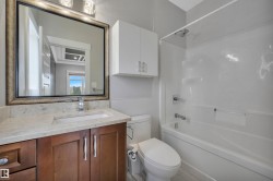 Wood-finish vanity with an undermount sink, light-toned countertop, and framed mirror - 