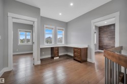 Wood-finish flooring throughout, L-shaped built-in desk with cabinetry, recessed lighting, and white window trim - 