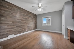 Wood-finish accent wall with coordinating wood-finish flooring, ceiling fan, and built-in cabinetry with a light-toned countertop - 