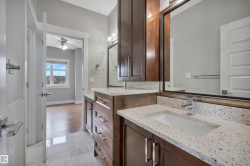 Double vanity with integrated sinks, speckled countertops, dark wood-finish cabinetry, and framed mirrors - 9054 24 Avenue Sw, Edmonton, AB 