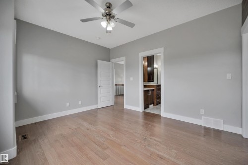 Spacious room featuring wood-finish flooring, light gray walls, a ceiling fan with integrated lighting, and white trim throughout - 9054 24 Avenue Sw, Edmonton, AB 