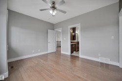 Spacious room featuring wood-finish flooring, light gray walls, a ceiling fan with integrated lighting, and white trim throughout - 