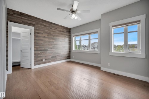 Wood-finish flooring with a textured accent wall and white trim - 9054 24 Avenue Sw, Edmonton, AB 