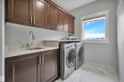 Laundry area featuring a window, built-in cabinetry, an undermount sink, a countertop, and large format floor tiling - 