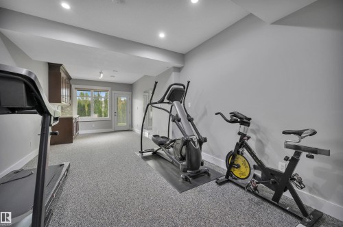 Recessed lighting, neutral gray walls, light gray carpet, built-in cabinetry with light-toned countertops, and a glass-paned exterior door - 9054 24 Avenue Sw, Edmonton, AB 