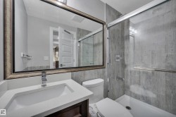 Bathroom featuring a built-in vanity with an undermount sink, a framed mirror, a toilet, a tub, and a shower with a glass enclosure and tile surround - 