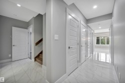 Recessed lighting illuminates the hall with light gray walls, white trim, and light-toned tile flooring - 
