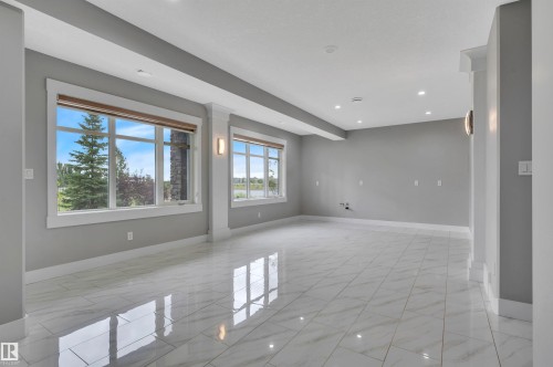 Spacious room with large windows, recessed ceiling lighting, wall sconces, column accents, and a polished tiled floor - 9054 24 Avenue Sw, Edmonton, AB 