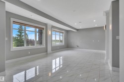 Spacious room with large windows, recessed ceiling lighting, wall sconces, column accents, and a polished tiled floor - 