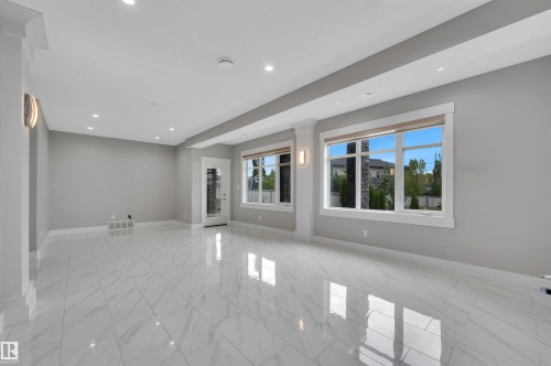 Spacious interior featuring large format tile flooring, recessed lighting, and ample natural light through multiple windows - 9054 24 Avenue Sw, Edmonton, AB 