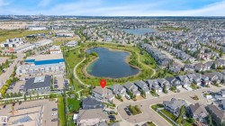 Aerial perspective showcasing a residential neighborhood, a central pond with walking paths, and commercial properties - 