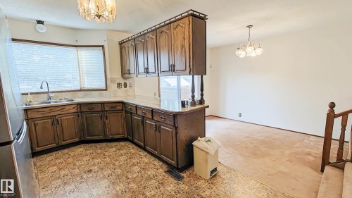 Kitchen featuring wood cabinetry, solid surface countertops, tile flooring, and a large bay window - 3031 79 Street Nw, Edmonton, AB 