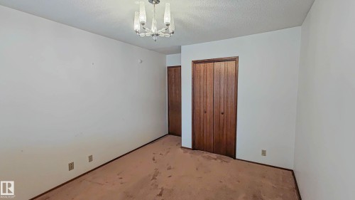 Double bi-fold wood doors, textured ceiling, and a ceiling-mounted light fixture - 3031 79 Street Nw, Edmonton, AB 