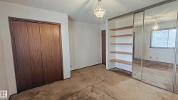 Mirrored closet doors, integrated shelving unit, wood-finish bi-fold closet doors, and overhead chandelier - 