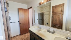 Dual vanity with integrated sinks, expansive mirror, wood-finish cabinetry, and built-in storage - 