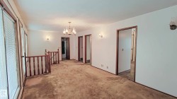 Spacious room with multiple windows, a decorative chandelier, and traditional wood-finish railing - 