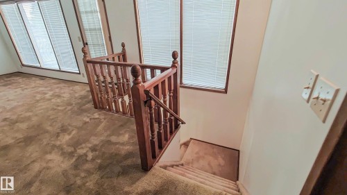 Staircase featuring wood balusters and railing, carpeted treads, and a landing with carpeted flooring - 3031 79 Street Nw, Edmonton, AB 