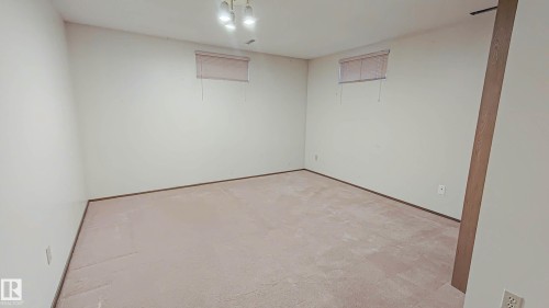 Light-toned carpeting, neutral wall finishes, and a flush-mount ceiling light fixture with three exposed bulbs - 3031 79 Street Nw, Edmonton, AB 