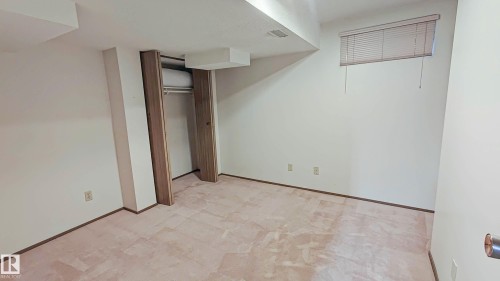 Recessed closet with a clothing rod, interior window with blinds, and light-toned carpeting - 3031 79 Street Nw, Edmonton, AB 