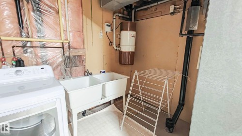 Laundry area featuring a dual basin utility sink and exposed insulation - 3031 79 Street Nw, Edmonton, AB 
