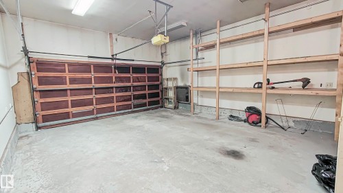 Garage spacious, high ceiling, with a paneled door, concrete flooring, overhead lighting, and built-in shelving - 3031 79 Street Nw, Edmonton, AB 