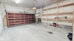 Garage spacious, high ceiling, with a paneled door, concrete flooring, overhead lighting, and built-in shelving - 