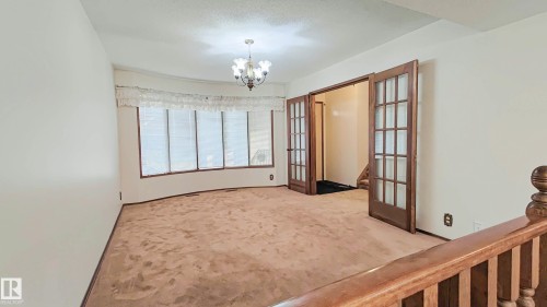 Bay window with multiple vertical blinds, classic chandelier, and wood-paneled French doors - 3031 79 Street Nw, Edmonton, AB 