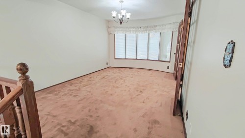 Bay window with vertical blinds, wood-finish doors, and a chandelier lighting fixture - 3031 79 Street Nw, Edmonton, AB 