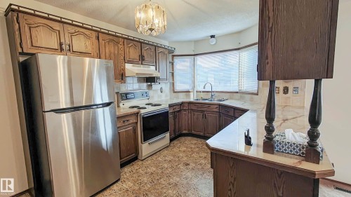 Kitchen featuring wood cabinetry, stainless steel refrigerator, built-in electric range, and a bay window - 3031 79 Street Nw, Edmonton, AB 