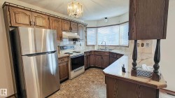 Kitchen featuring wood cabinetry, stainless steel refrigerator, built-in electric range, and a bay window - 