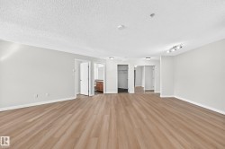 Spacious room featuring wood-finish flooring, light gray walls, and track lighting - 