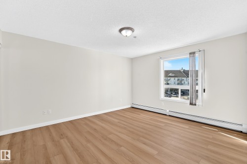Wood-finish flooring, white walls, ceiling-mounted light fixture, and a large window - #1303 330 Clareview Station Dr Nw, Edmonton, AB 