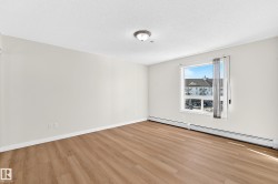 Wood-finish flooring, white walls, ceiling-mounted light fixture, and a large window - 