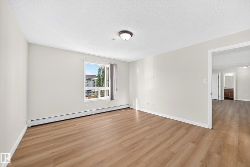 Wood-finish flooring, neutral wall tones, window with vertical blinds, and ceiling-mounted lighting fixture - #1303 330 Clareview Station Dr Nw, Edmonton, AB 