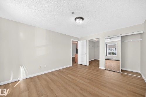 Wood-finish flooring, neutral wall tones, flush mount lighting, sliding mirrored closet doors, and walk-in closet space - #1303 330 Clareview Station Dr Nw, Edmonton, AB 