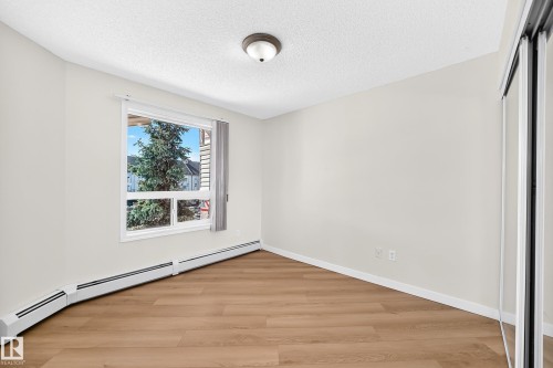 Wood-finish flooring, white walls, and a window with exterior tree landscaping - #1303 330 Clareview Station Dr Nw, Edmonton, AB 