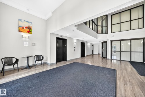 Spacious common area featuring wood-finish flooring, multiple elevators, and large windows - #1303 330 Clareview Station Dr Nw, Edmonton, AB 