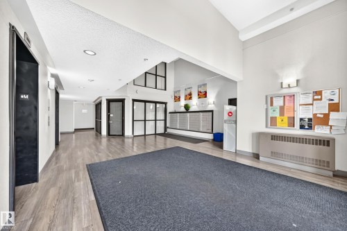 Building lobby featuring wood-finish flooring, recessed lighting, wall-mounted light fixtures, and a mail area - #1303 330 Clareview Station Dr Nw, Edmonton, AB 